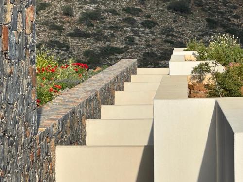 a stone wall with stairs in front of flowers at Maison Meltem in Agia Pelagia