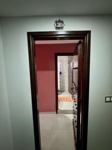 a doorway to a room with a red wall and a mirror at La Perle De Briech in Asilah