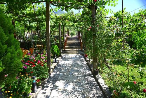 a garden path with a bunch of flowers and trees at Kulla e Vjeter (Bar Restaurant, Guesthouse, Parking and Camping) in Koman