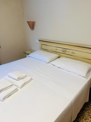 a white bed with two white towels on it at Santa croce 241 in Venice
