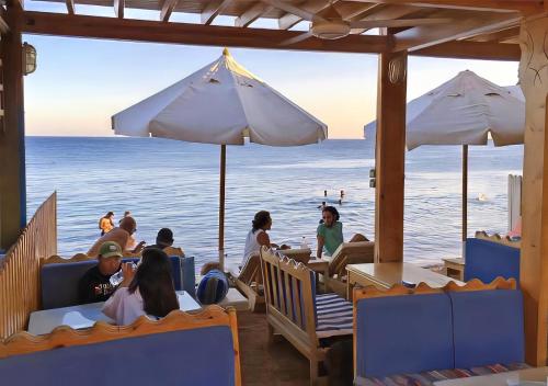 a group of people sitting at a restaurant on the beach at Red Sea Relax Hotel in Dahab
