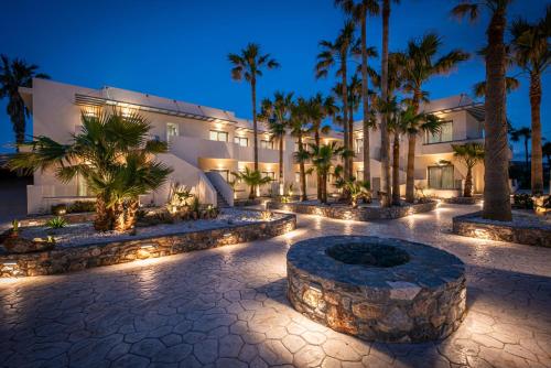 an exterior view of a building with palm trees and lights at Saint George Gournes Bay in Gournes