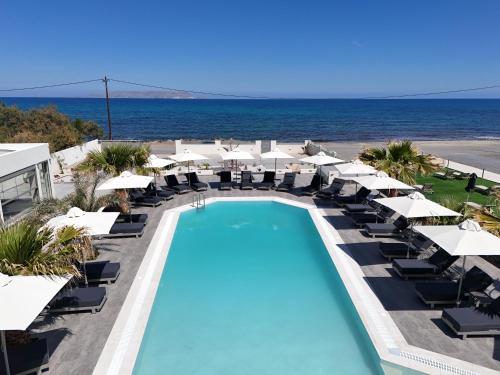 a swimming pool with umbrellas and chairs and the ocean at Saint George Gournes Bay in Gournes