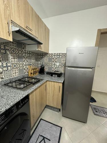 a kitchen with a stainless steel refrigerator and wooden cabinets at Superbe appartement Anza in Agadir