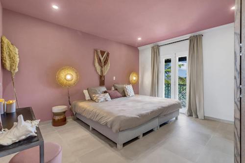 een slaapkamer met een groot bed met roze muren bij Apartment Turtle at Windsock Beach in Kralendijk