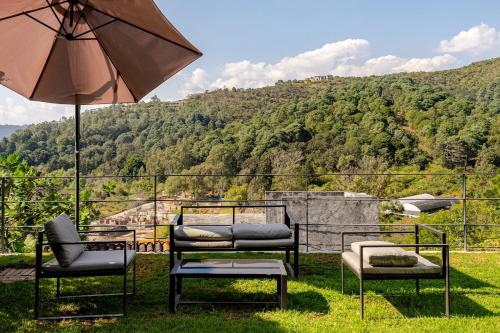 a patio with chairs and an umbrella and a view at LUXO Casa en Valle de Bravo con jacuzzi y espectacular vista al lago in Valle de Bravo