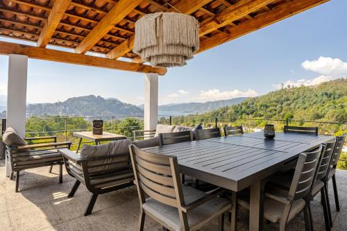 an outdoor dining area with a wooden table and chairs at LUXO Casa en Valle de Bravo con jacuzzi y espectacular vista al lago in Valle de Bravo