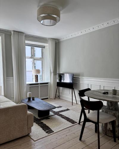 a living room with a couch and a table and a piano at Stylish Apartment with Rooftop in Trendy Vesterbro in Copenhagen