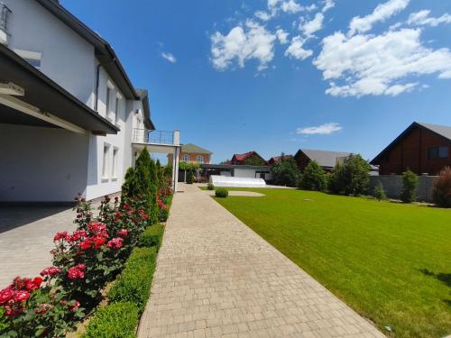 a brick walkway next to a house with flowers at Sunhouse in Sanzhiyka