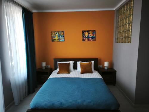 a bedroom with an orange wall and a bed with pillows at Sunhouse in Sanzhiyka