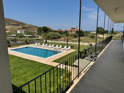 a balcony with a swimming pool and lounge chairs at Kirykos Otel in Gökçeada