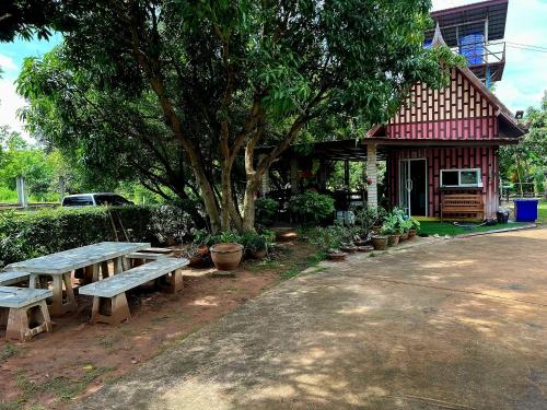 a picnic table in front of a building with a tree at Rawinnipha's Resort & Garden Khonkaen in Khon Kaen