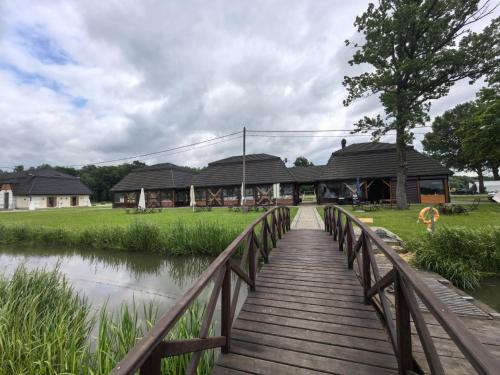 a wooden bridge over a river with a building at Pokoje Gościnne "Rybackie Zacisze" w Starzawie in Stubno