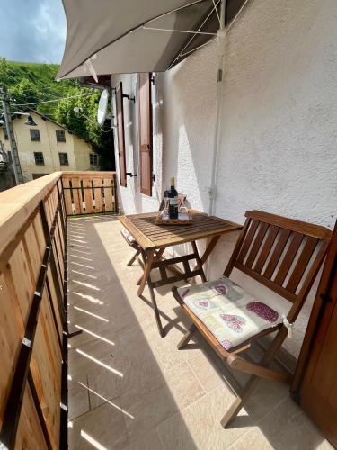 a patio with a wooden table and chairs and an umbrella at My Dolomites Home in Livinallongo del Col di Lana