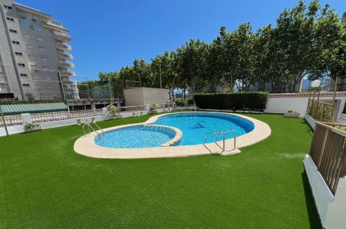 ein Swimmingpool in einem Hof mit grünem Gras in der Unterkunft Apartamento Acogedor con Piscina, Cerca de la Playa in Playa de Gandia