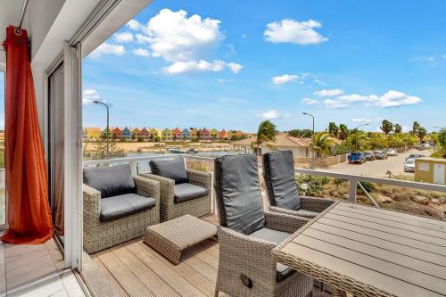 eine Terrasse mit Stühlen und einem Tisch auf einem Balkon in der Unterkunft Caribbean Court Apartment Djòdjò in Kralendijk