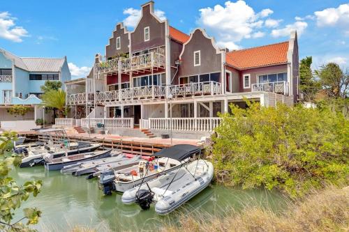 ein großes Haus mit im Wasser angedockten Booten in der Unterkunft Caribbean Court Apartment Djòdjò in Kralendijk