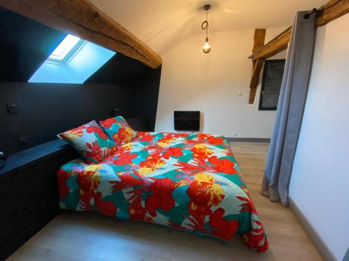 a bedroom with a bed with a colorful comforter at L'Alcôve, maison d'artistes in Sacquenay