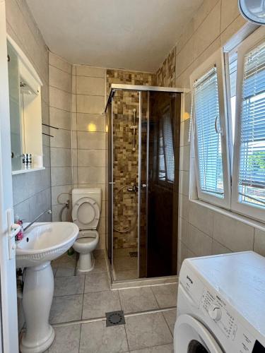 une salle de bain avec toilettes et lavabo et une machine à laver dans l'établissement Hida Ile apartments, à Ulcinj