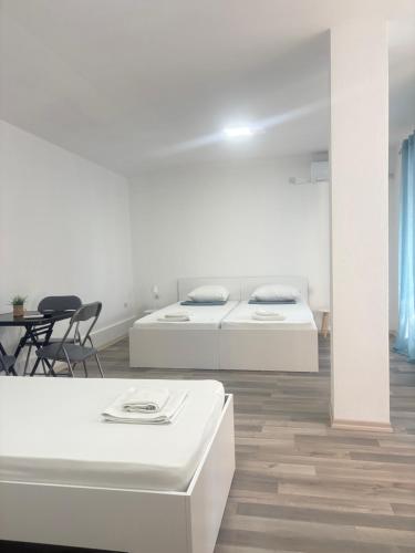 two beds in a white room with a table and chairs at TIKI Apartments in Gevgelija