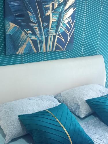 a bedroom with blue pillows and a painting on the wall at Ema Lux Apartments in Soko Banja