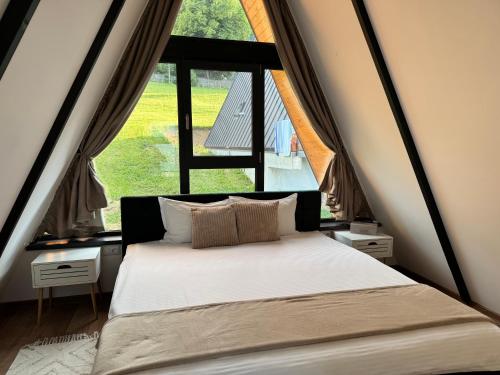 a bed in a room with a large window at Ambiance Aframe in Câmpulung Moldovenesc