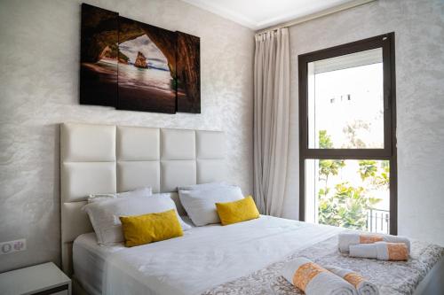 a bedroom with a large white bed with yellow pillows at Modern&Luxe Apt in Taghazout Bay in Taghazout