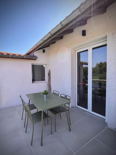 ein grüner Tisch und Stühle auf einer Terrasse in der Unterkunft Cap sur l'EDEN in Capbreton