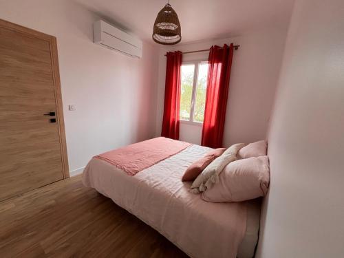 ein Schlafzimmer mit einem Bett und einem Fenster mit roten Vorhängen in der Unterkunft Cap sur l'EDEN in Capbreton