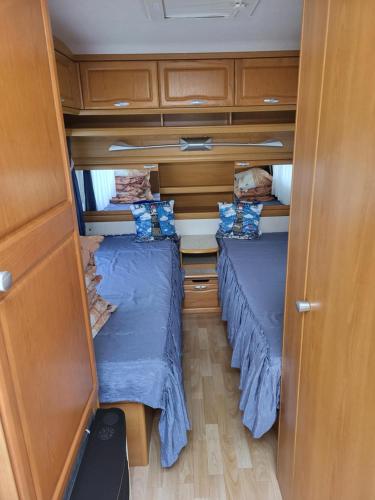 two beds in a small room with wooden cabinets at Przyczepa campingowa in Grzybowo