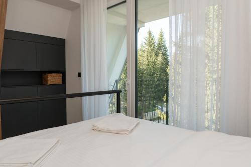 een slaapkamer met een bed en een groot raam bij Engadin's Family Apartment in Jahorina