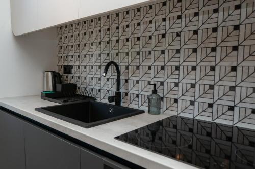 een keuken met een zwarte wastafel en een tegelmuur bij Engadin's Family Apartment in Jahorina