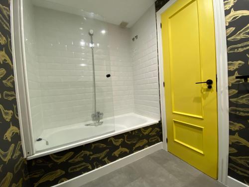 a bathroom with a tub and a yellow door at Piso Céntrico 120m2 + parking propio (O Grove) in O Grove