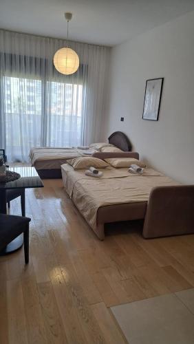 una camera da letto con due letti, un tavolo e una lampada di Studio apartment a Bar