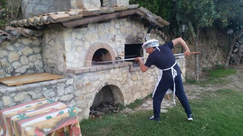 a man holding a baseball bat in front of a stone oven at Villa Greco in Rossano