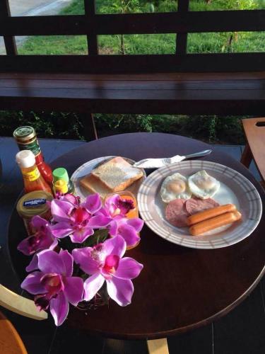 a table with a plate of food and flowers on it at Rawinnipha's Resort & Garden Khonkaen in Khon Kaen