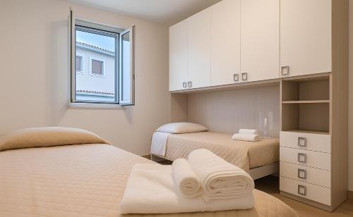 a white bedroom with two beds and a window at B&B Tolomeo Residence - 3 - Intero alloggio in Vibo Valentia Marina