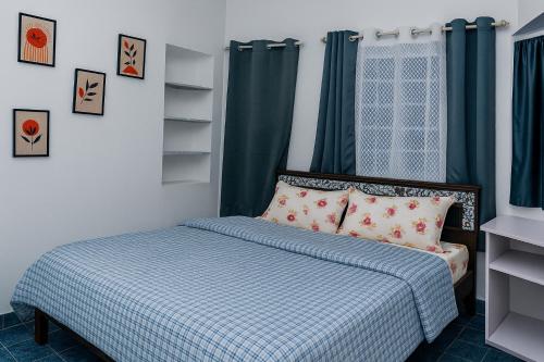 クーヌールにあるPleasant Heights Homestayのベッドルーム1室(青と白の掛け布団付きのベッド1台付)