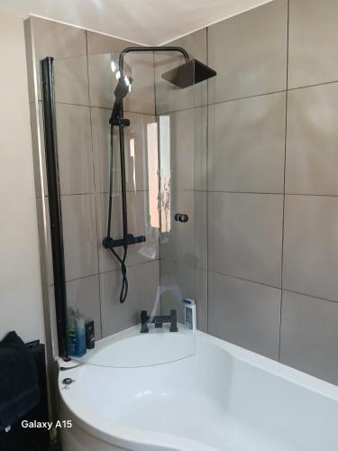 a bathroom with a shower with a white sink at 2 bedroomed homely house in Manchester