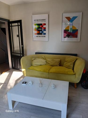 a living room with a yellow couch and a white coffee table at 2 bedroomed homely house in Manchester