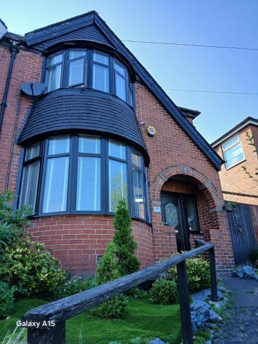 a red brick house with a large window at 2 bedroomed homely house in Manchester