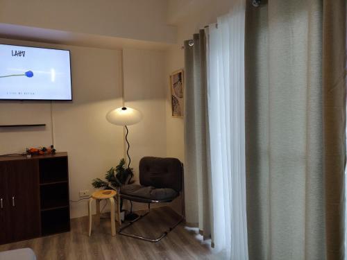a living room with a chair and a flat screen tv at Cozy Staycation Near Cebu Airport with Pool & Gym , Free Wifi in Pusok