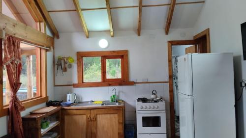 a small kitchen with a refrigerator and a stove at Refugio entre Coihues in Melipeuco