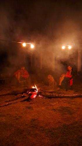 a group of people standing around a fire at night at Camping Caldeirão Furado in São Thomé das Letras