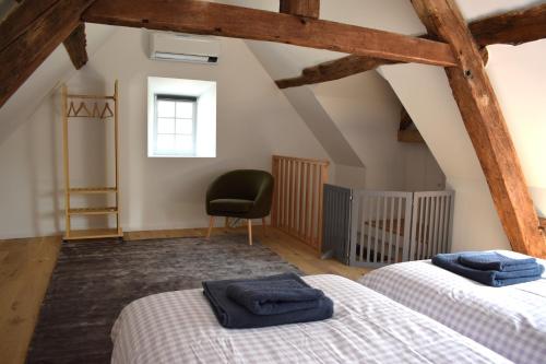 een zolderslaapkamer met twee bedden en een stoel bij Charmante maison avec jardin et air conditionné au coeur d'un village historique ! in Verneuil-en-Bourbonnais