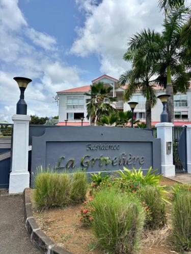 a sign in front of a building with palm trees at Precious Jungle, à seulement 5 min de Destreland in Baie-Mahault