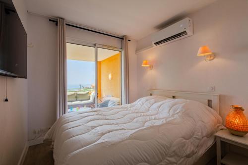 une chambre avec un lit et une grande fenêtre dans l'établissement Résidence le Hameau des Issambres - maeva Home - Appartement rénové 3 pièces 6 personnes - Prestige - super Home MAE-1614, aux Issambres