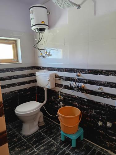 a bathroom with a toilet and a bucket at Tashi Khangsar in Padam