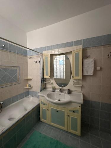Un baño con lavabo, bañera y espejo. en Neraida view, en Neráïdha