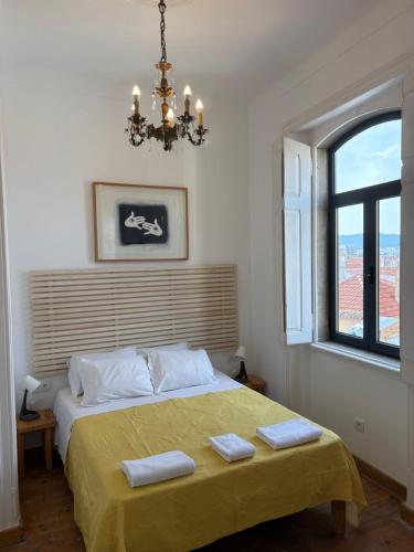 a bedroom with a bed with a chandelier and a window at Sea the City Setúbal in Setúbal